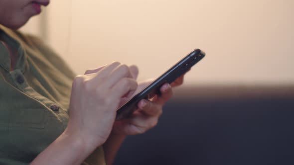 Asian woman using mobile during night time and she is chatting with her friends.