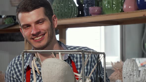 Young Cheerful Potter Taking Photos of a Sculpture He Made alt