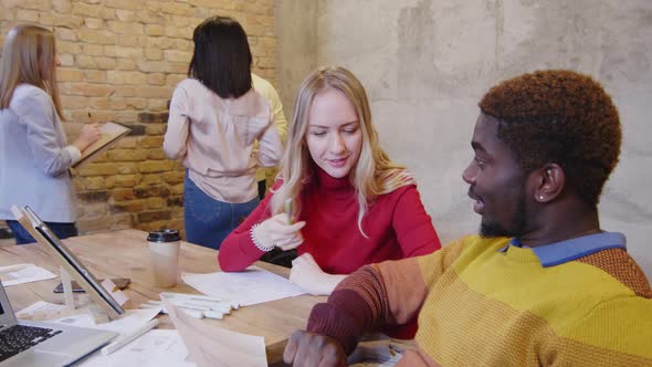 Designers Discussing Interior Plan while Colleagues Cooperating in Office