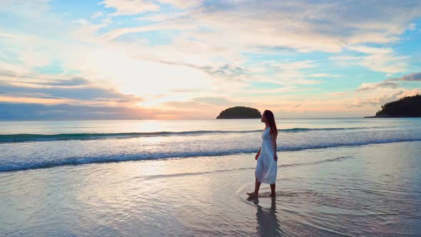 Young woman traveler walking and enjoying beautiful Sunset on the tranquil beach