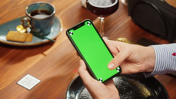Woman Using Smartphone with Chroma Green Screen Online Menu in Cafe alt