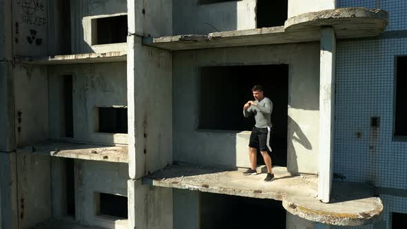 Male Fighter Practicing on Abandoned Building Balcony. Pan Around Drone View of Powerful Sportsman