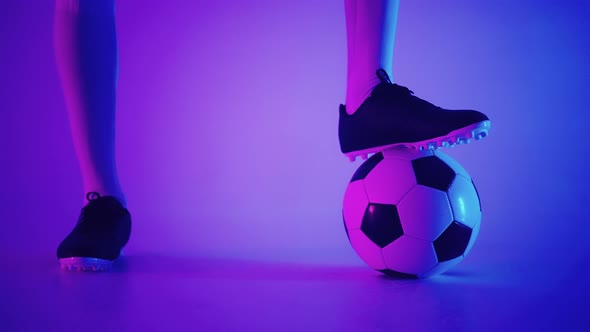 Closeup of the Foot of a Professional Black Football Player Standing on the Ball in Slow Motion in alt