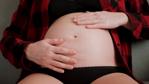 Slow motion shot of pregnant woman stroking baby belly with hands alt