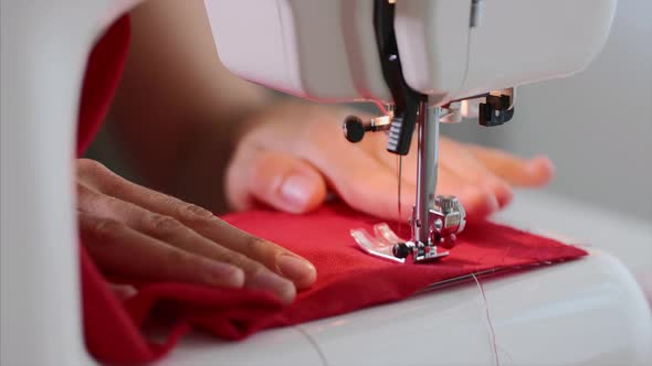 Hands of Woman Tailor Sewing Red Clothing on Sewing Machine with Straight Seam. alt