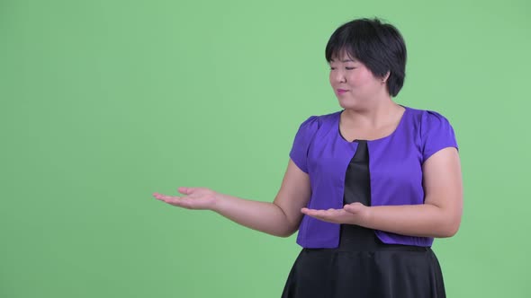 Happy Young Overweight Asian Woman Showing Something alt