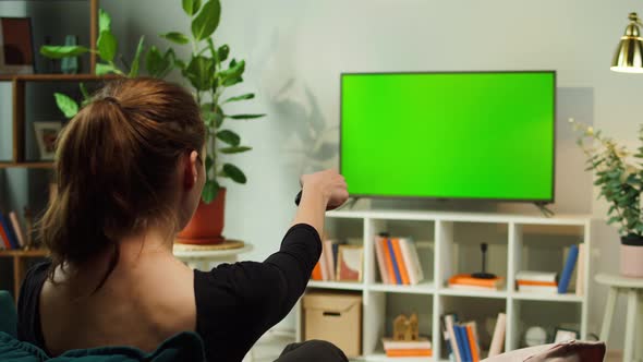 Woman Watching TV with Green Screen in Living Room Back View alt