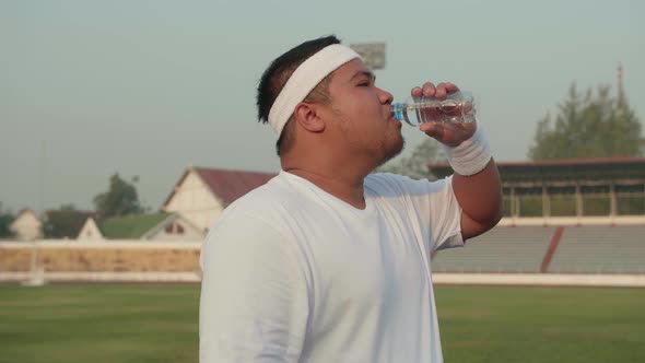 Overweight Man Drink Water At Stadium alt