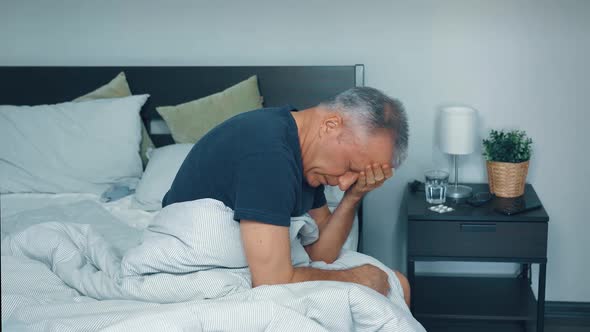 A Sick Middleaged Man is Lying in Bed and is Suffering at Home From a Headache and a Severe Cold