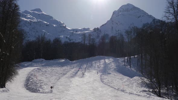 Skiers And Snowboarders Skiing Down On Slope On Sunny Winter Day In Mountain alt