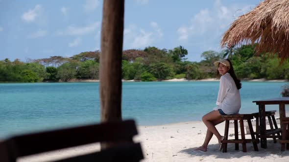 Slow motion of a young woman sitting on the beach by the sea