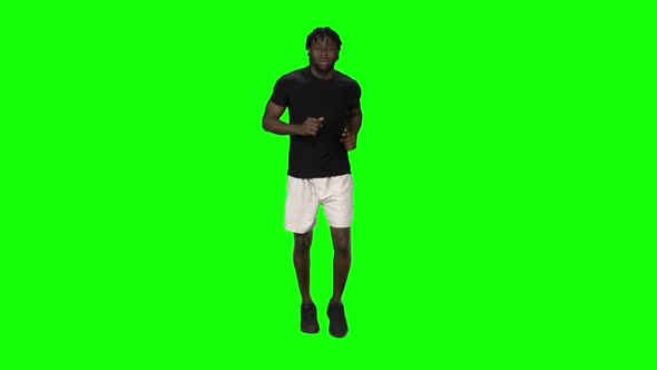 African American Man Is Running at Green Screen, Chroma Key. Front View. Slow Motion alt