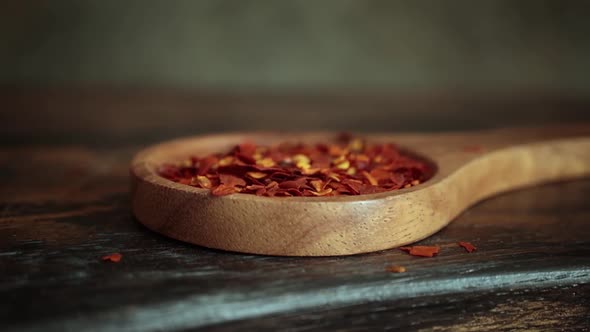 Flakes of Red Hot Chili Pepper in Wooden Spoon Closeup on a Kitchen Table alt