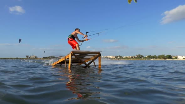 Kiteboarding and riding a kite board off a ramp to jump. alt