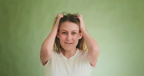 Relaxed Woman Touches Blonde Hair By Hands Posing on Green alt