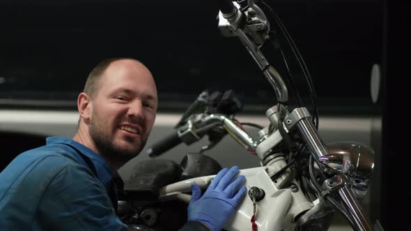 guy mechanic in blue overalls next to a motorcycle