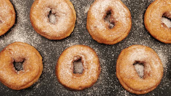 Rows of doughnuts with sugar powder on the black desk