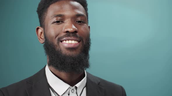 A Young Handsome Black Bearded Man in a Tuxedo is Smiling and Looking at the Camera Full Size alt