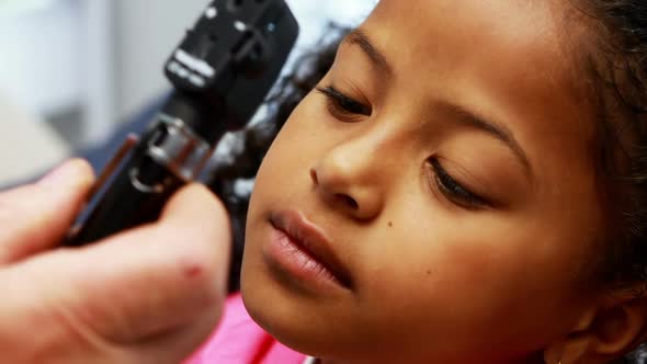 Doctor examining patients eye with otoscope alt