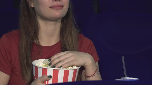 The Young Lady Is Eating Popcorn During the Screening