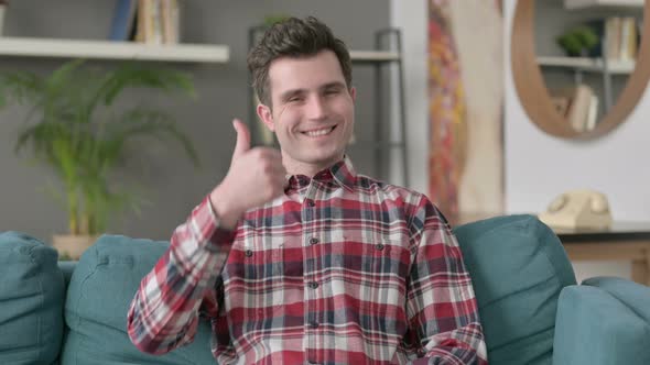 Portrait of Man Showing Thumbs Up While Sitting on Sofa alt