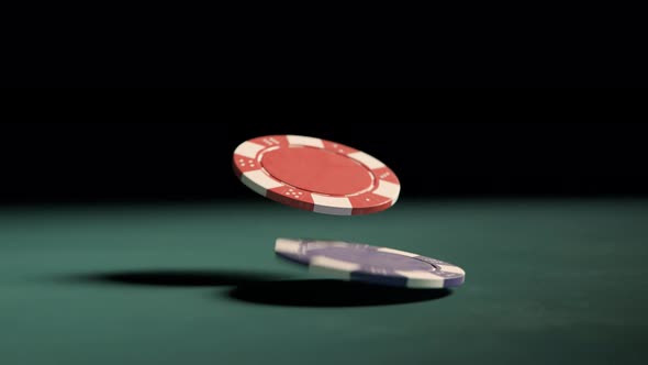 Two casino chips falling on the table. Red and blue tokens on a green table. alt