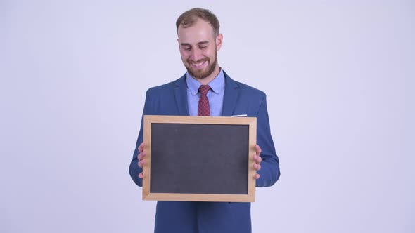 Happy Bearded Businessman Thinking While Holding Blackboard