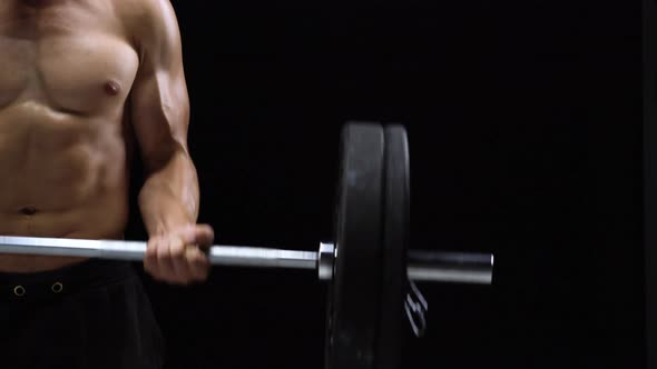 Man is Doing Exercises with a Barbell Training on a Black Background in the Studio alt