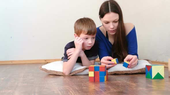 Mother and Son Playing Wooden Colored Education Toy Blocks Lying on the Floor.