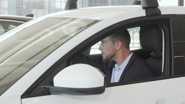 Happy Handsome Man Examining Interior of a New Car Sitting Inside