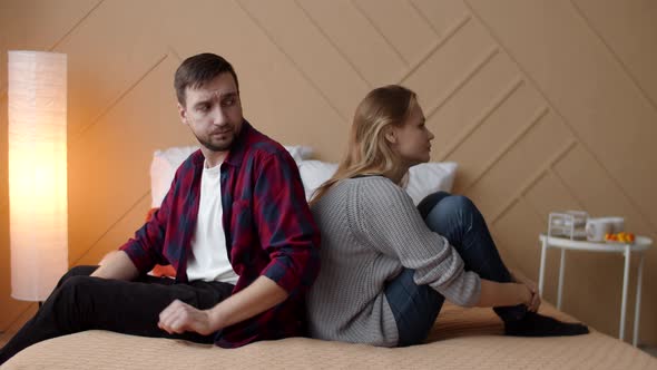 Man and Woman are Sitting on Bed with Their Backs Each Other After an Argument Man Tries to Touch alt