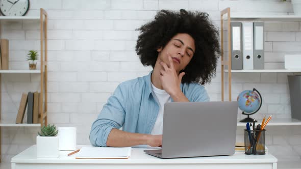 Thoughtful Student Guy Looking At Laptop Thinking Learning Online Indoors alt