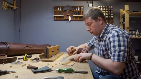 Tailor in a Plaid Shirt Creates a Leather Purse for Individual Design in the Workshop