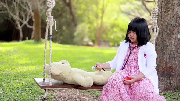 A young Asian woman playing as a teddy bear doctor
