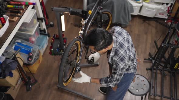 Top view of Asian senior man owner repairing and checking wheels and gears of bicycle