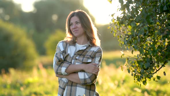 Portrait of an attractive blonde woman smiling in the park at sunset. alt