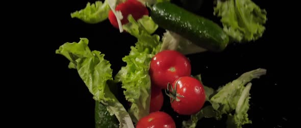 Tasty Tomatoes Cucumbers and Lettuce Fly Around on a Black Background in Slow Motion Shot Water alt