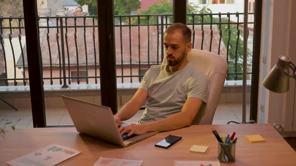 Crane Shot of Manager of Start Up Company Working on the Laptop in Warm Sunset Light alt