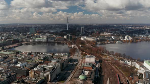 Wide Aerial View of Car and Train Traffic Across Binnenalster Lake with Hamburg Panorama in the alt