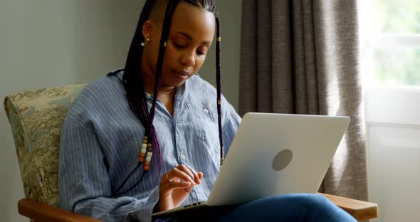 Front view of young black woman working on laptop in a comfortable home 4k alt