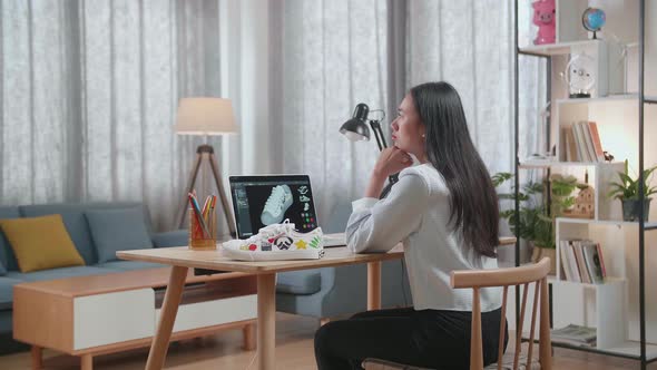 Asian Female Footwear Designer Thinking Then Raising Index Finger While Designing Shoe On A Laptop alt
