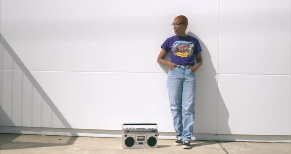 This video is about a medium shot of a young African American women against white wall listening to alt