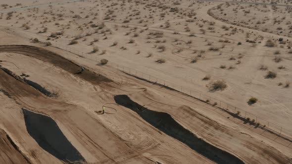 Motocross motorcycle rider jumping on circuit in Mojave Desert, Aerial view alt