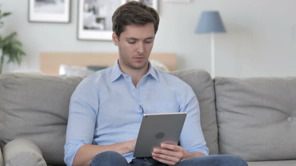 Young Man Browsing Internet on Tablet alt