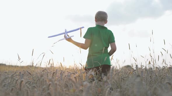 A Boy with an Airplane in His Hands Runs in the Park