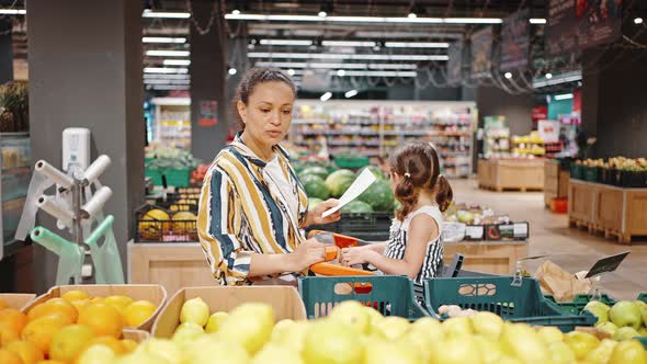 Lovely Family Mother and Little Daughter Buy Lemons in the Hypermarket in the Fruit Section alt