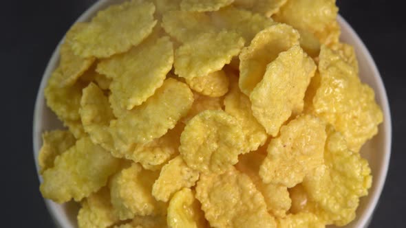 Crispy hot corn flakes with smoke rotating in bowl close up, dry healthy breakfast alt