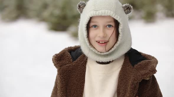 Portrait of happy smiling cute little girl child in winter clothes looking at camera outdoors 