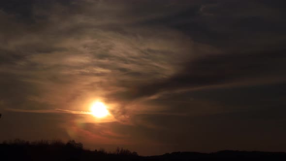 Time lapse amazing sunset shining through soft clouds going to darkness