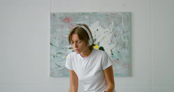 Young Woman Is Dancing on Bed, Wearing Wireless Headset, Close Up alt